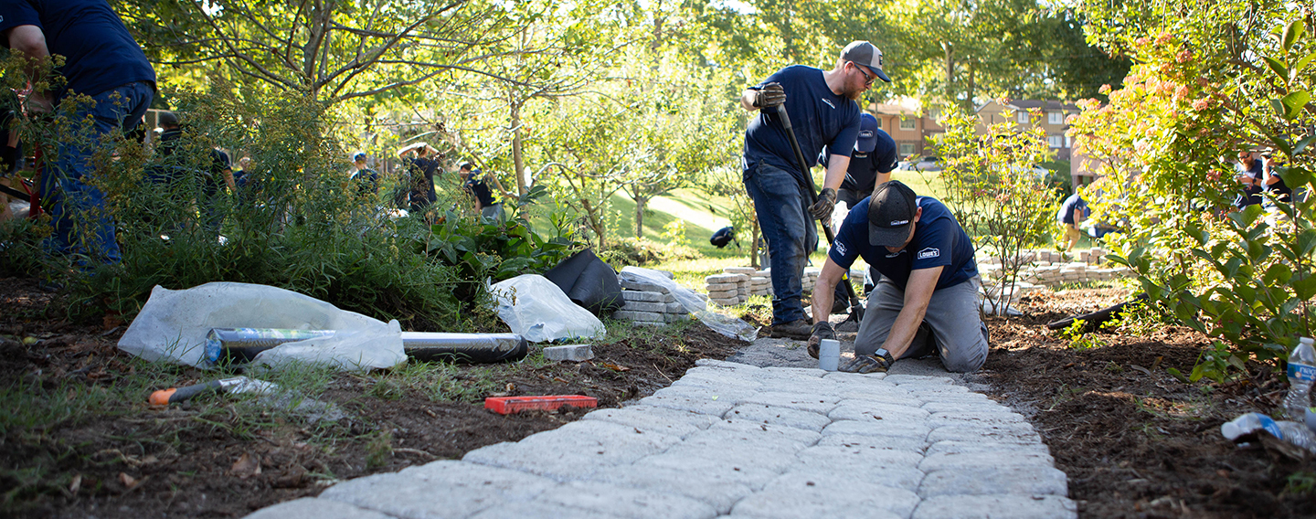 Lowe's volunteers laying pavers in garden